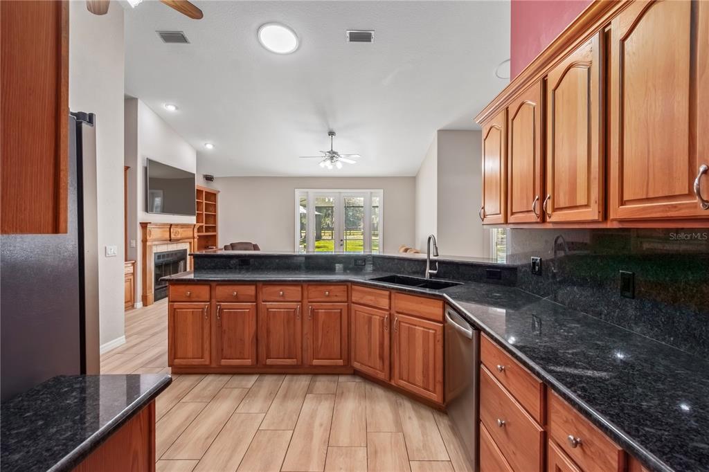 1969 Northwest 111th Loop Ocala, FL 34475 - Photo 17 of 48 a kitchen with stainless steel appliances granite countertop wooden cabinets a sink and dishwasher a refrigerator with wooden floor