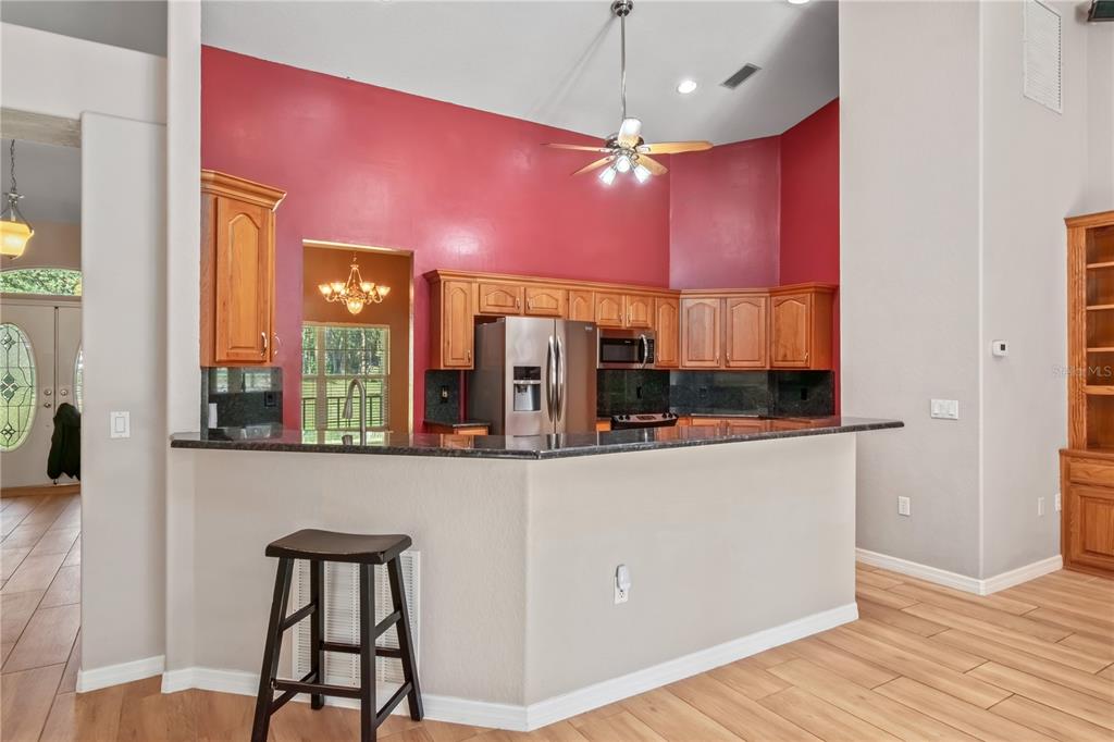 1969 Northwest 111th Loop Ocala, FL 34475 - Photo 19 of 48 a kitchen with stainless steel appliances kitchen island granite countertop a refrigerator a stove and a wooden floors