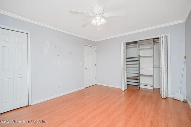 an empty room with wooden floor closet and windows