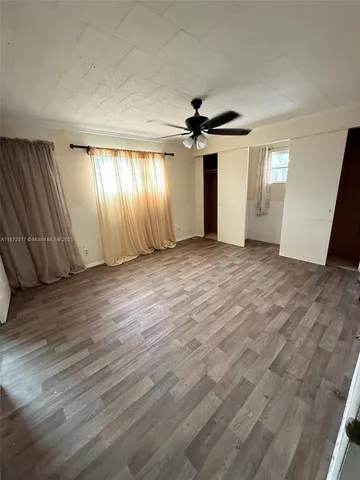 an empty room with windows and fan