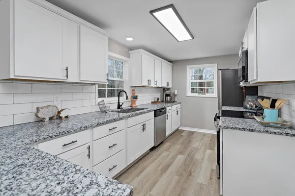 a kitchen with granite countertop a sink a window stainless steel appliances and cabinets