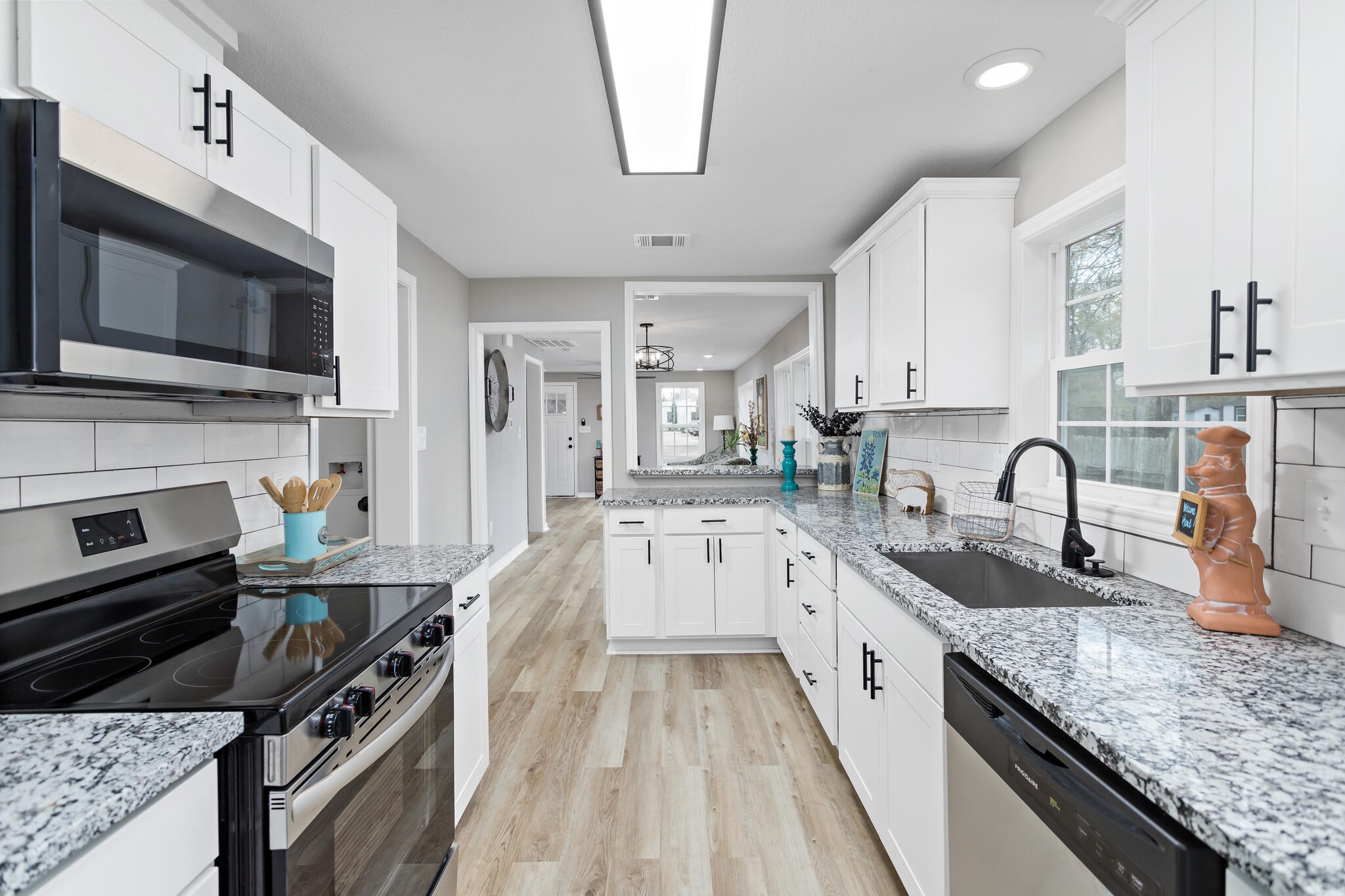 2320 Delaware Street Beaumont, TX 77703 - Photo 12 of 27 a kitchen with stainless steel appliances granite countertop a stove top oven a sink dishwasher and a microwave with wooden floor