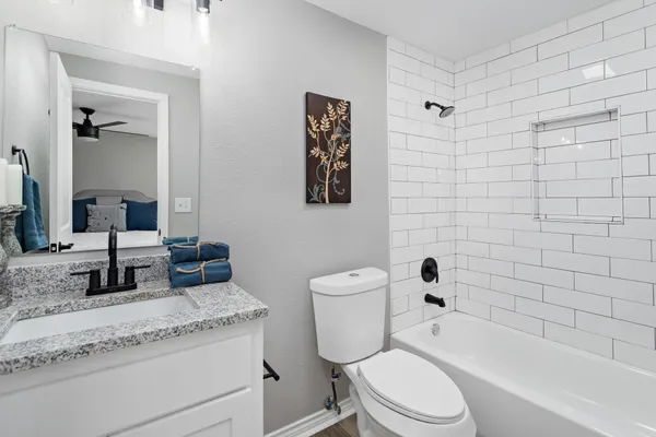 a bathroom with a granite countertop toilet a sink and bathtub
