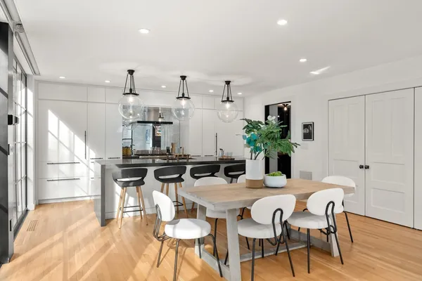 a kitchen with stainless steel appliances kitchen island granite countertop a dining table chairs and refrigerator