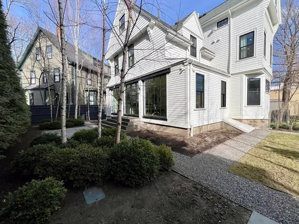 a view of a white house with a small yard and plants