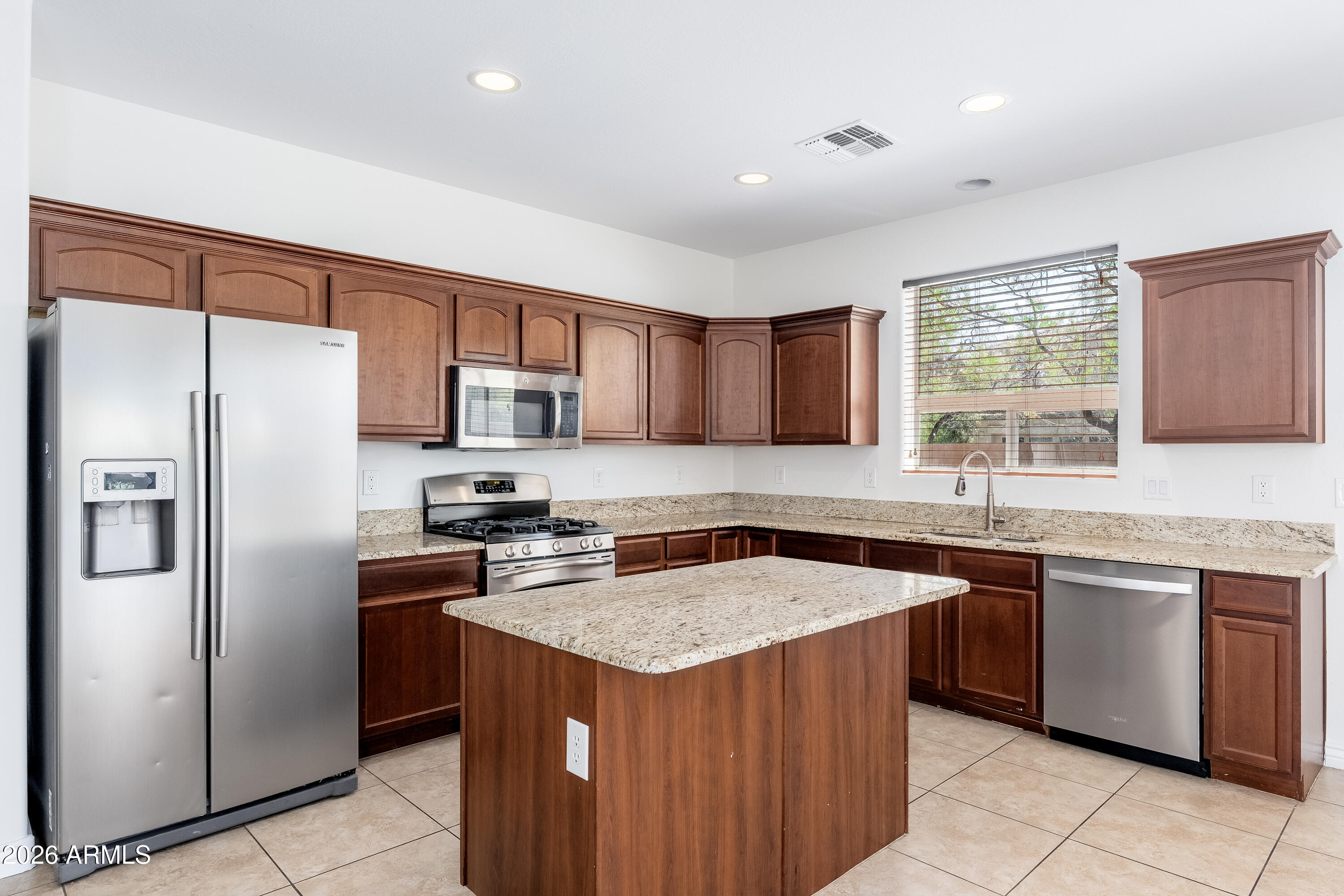 4317 East Folgers Road Phoenix, AZ 85050 - Photo 10 of 40 a kitchen with stainless steel appliances granite countertop a stove a sink dishwasher a refrigerator and a microwave oven with wooden cabinets