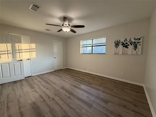 a view of an empty room with a window and wooden floor