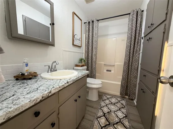 a bathroom with a granite countertop sink toilet and shower