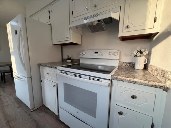 a kitchen with stainless steel appliances granite countertop white cabinets and a stove