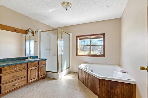 a spacious bathroom with a granite countertop tub shower and mirror