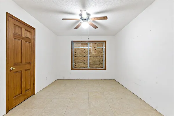 an empty room with windows and fan