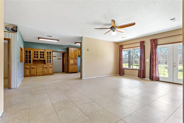 a view of an empty room with a window and kitchen view