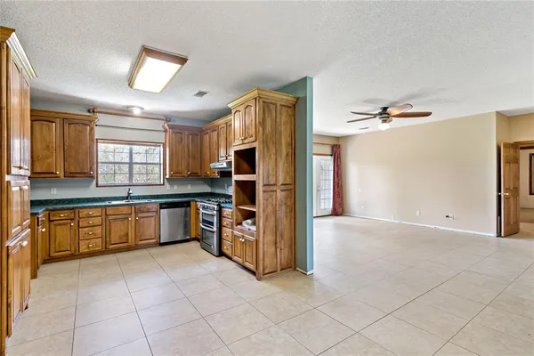 a large kitchen with granite countertop a refrigerator and a stove top oven