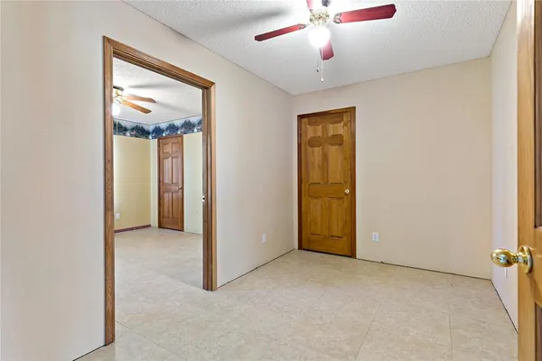 an empty room with a chandelier fan and windows