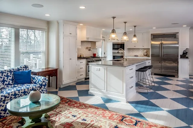 a kitchen with stainless steel appliances kitchen island granite countertop a sink a stove a dining table and chairs