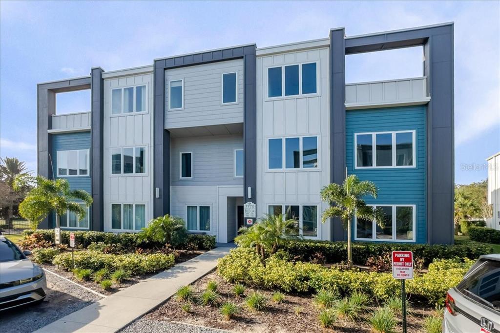 a front view of a house with lots of flowers around