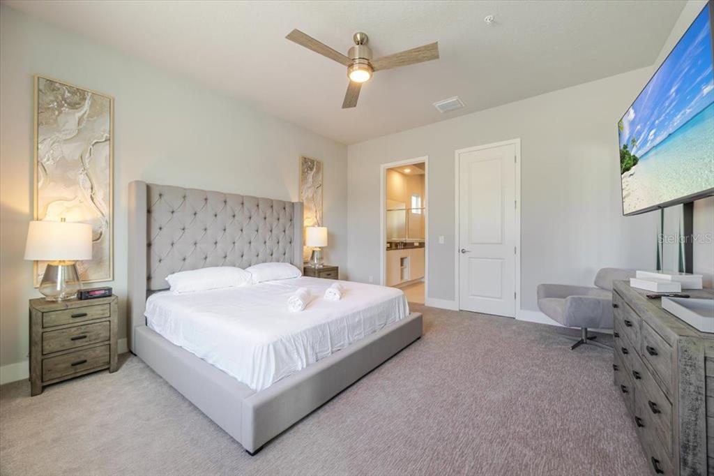 7770 Sandy Ridge Drive, Unit 144 Reunion, FL 34747 - Photo 20 of 22 a large bed sitting in a bedroom next to a window and a chandelier