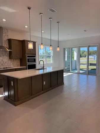 a kitchen with stainless steel appliances kitchen island granite countertop a stove a sink and a wooden floors