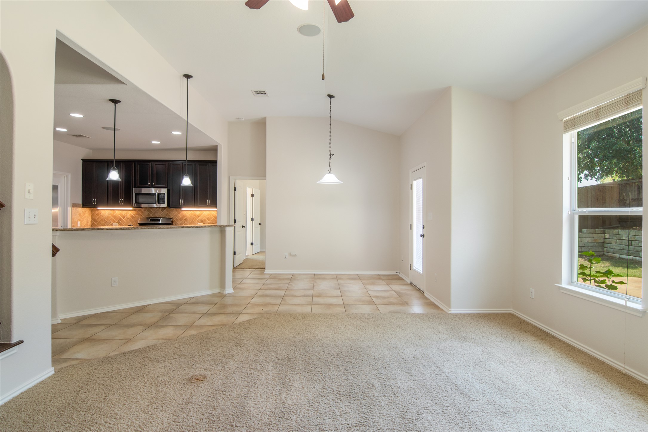12104 Broten Street Austin, TX 78748 - Photo 6 of 32 A combined living and dining area boasts vaulted ceilings, tile, and carpeted flooring, creating an adaptable interior.