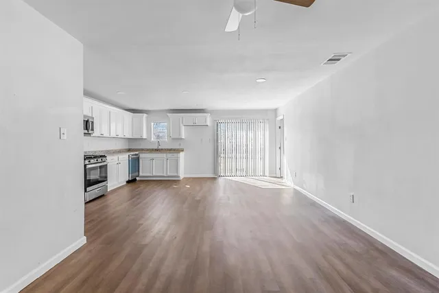 an empty room with wooden floor cabinet and windows