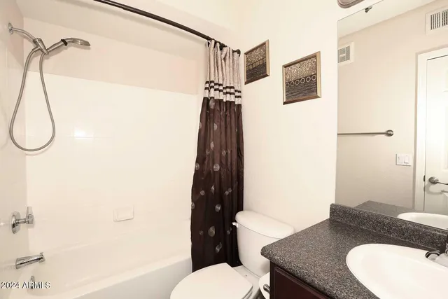 a bathroom with a granite countertop toilet sink and shower curtain
