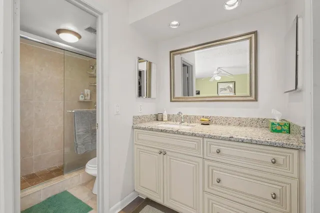 a bathroom with a granite countertop sink a large mirror a shower and a bathtub