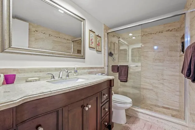 a bathroom with a granite countertop sink toilet a mirror and shower