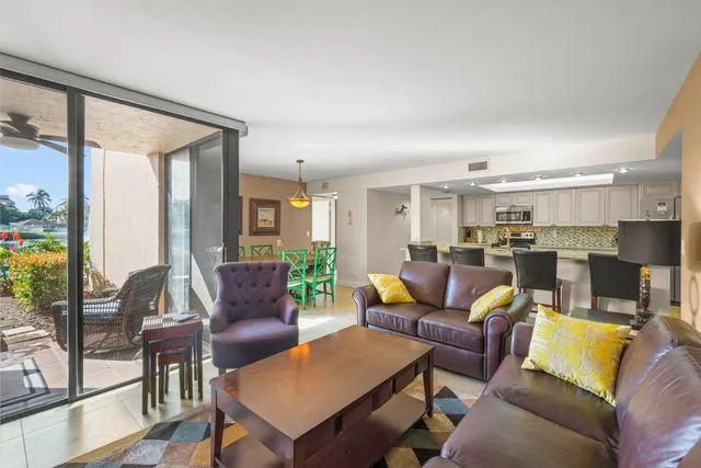 a living room with furniture kitchen view and a large window
