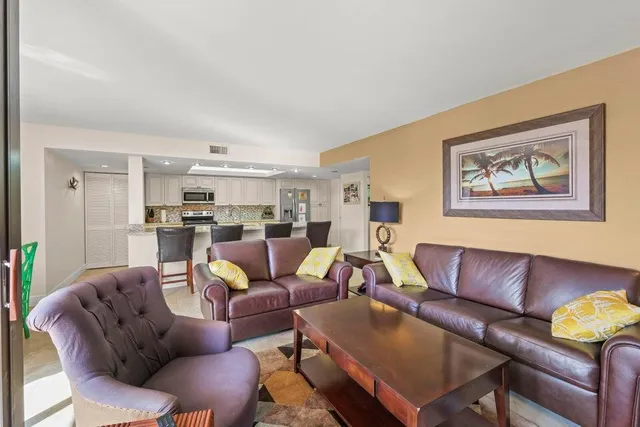 a living room with furniture kitchen view and a window