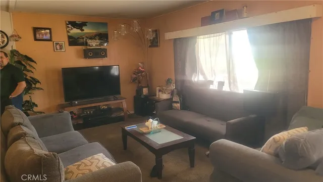 a living room with furniture a flat screen tv and a window
