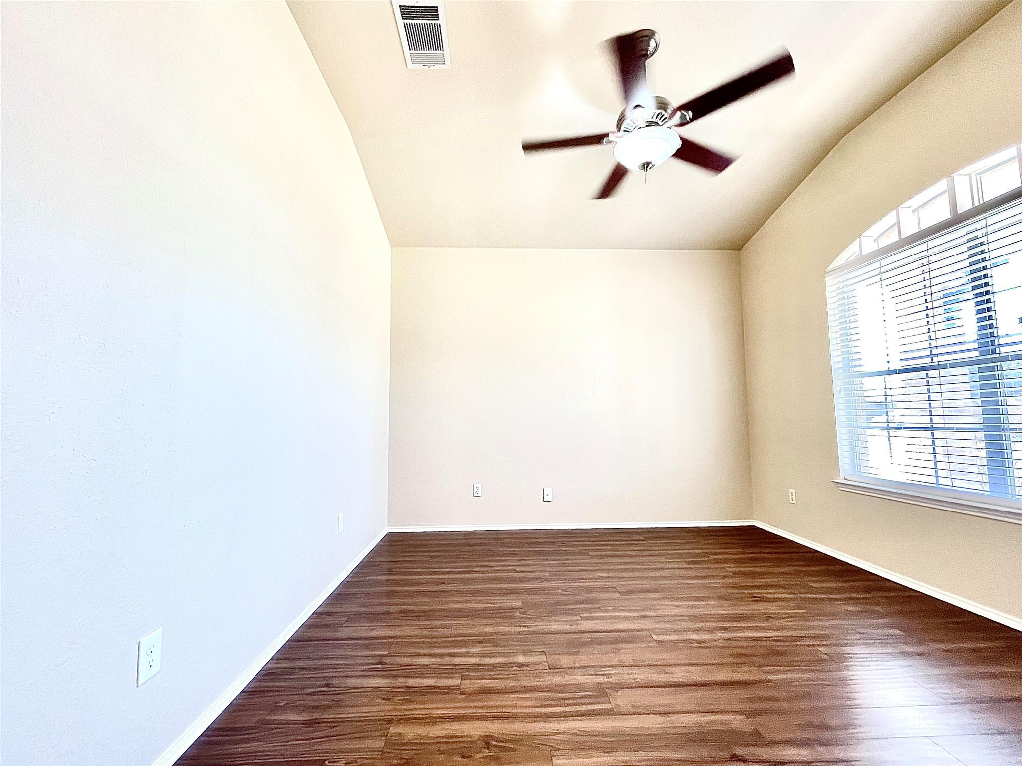 508 Emma Rose Trail Leander, TX 78641 - Photo 27 of 40 A room with vaulted ceilings, rich hardwood flooring, and a large arched window with blinds.