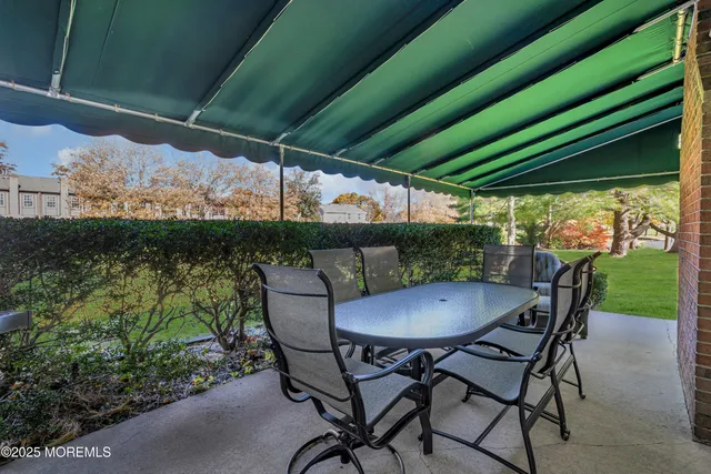 a view of patio with table and chairs under an umbrella with a small yard