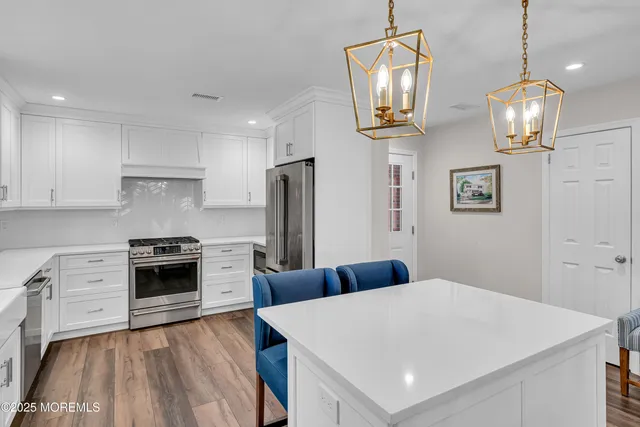 a kitchen with stainless steel appliances a stove refrigerator and wooden floor