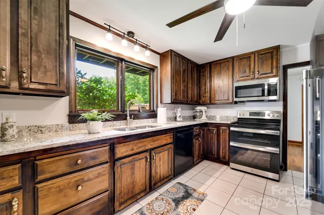 a kitchen with stainless steel appliances kitchen island granite countertop a sink window and cabinets
