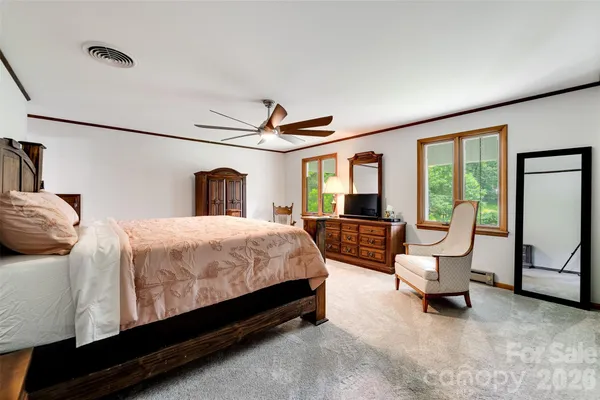 a spacious bedroom with a bed chairs and large window