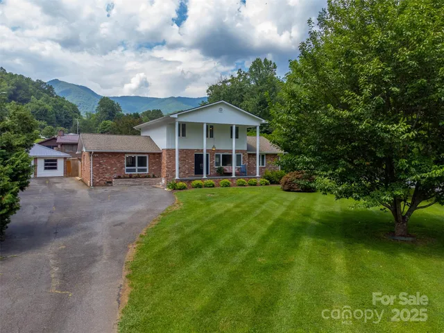 a view of a house with a big yard potted plants and large tree