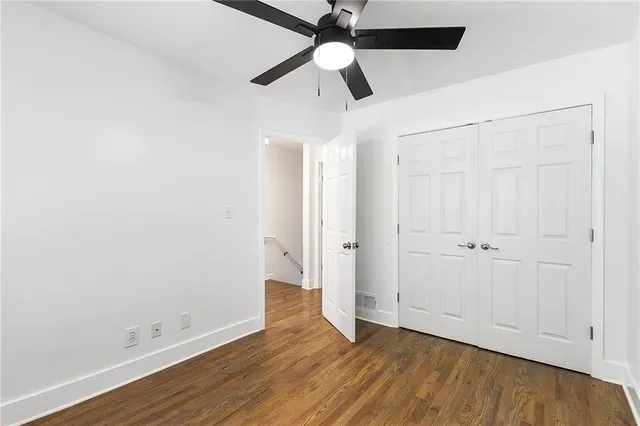 an empty room with wooden floor a ceiling fan and closet