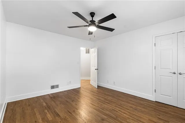 an empty room with wooden floor and ceiling fan