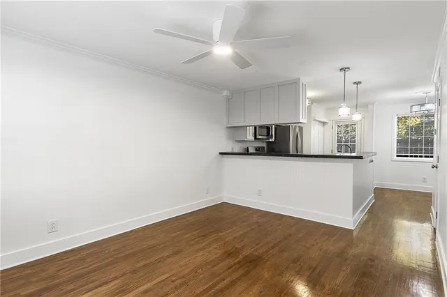 a view of empty room with wooden floor and kitchen view