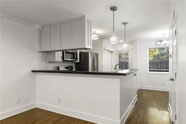 a kitchen with stainless steel appliances granite countertop a sink a microwave a refrigerator and white cabinets