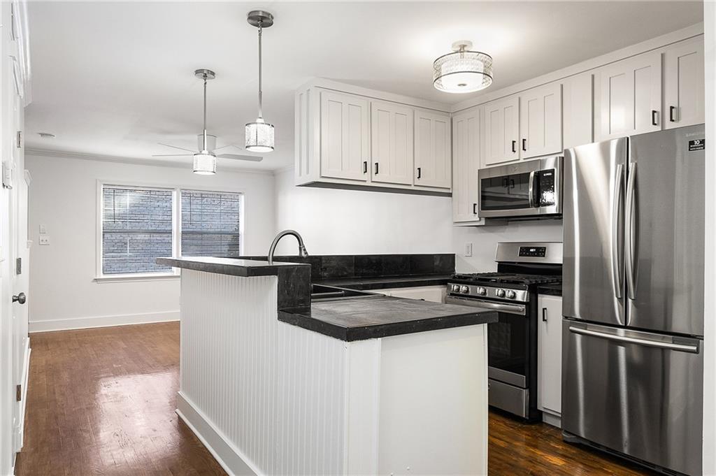 2232 Dunseath Avenue Northwest, Unit 309 Atlanta, GA 30318 - Photo 6 of 25 a kitchen with granite countertop a refrigerator a sink dishwasher a stove and white cabinets with wooden floor