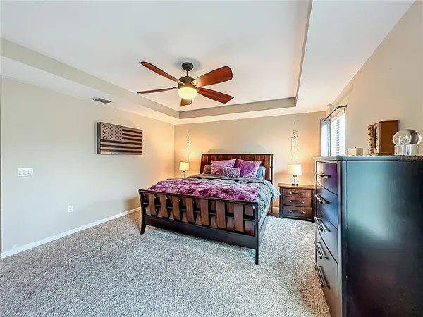 a bedroom with a bed a dresser and potted plant
