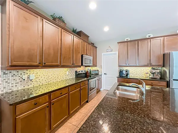 a kitchen with granite countertop wooden cabinets a stove top oven a sink and dishwasher