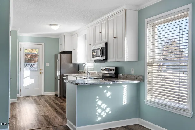 a kitchen with stainless steel appliances granite countertop a refrigerator a stove a sink and dishwasher with wooden floor