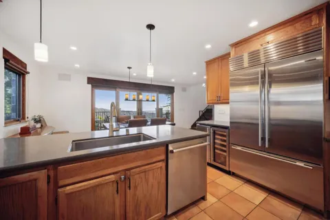 a kitchen with stainless steel appliances kitchen island granite countertop a sink and a refrigerator