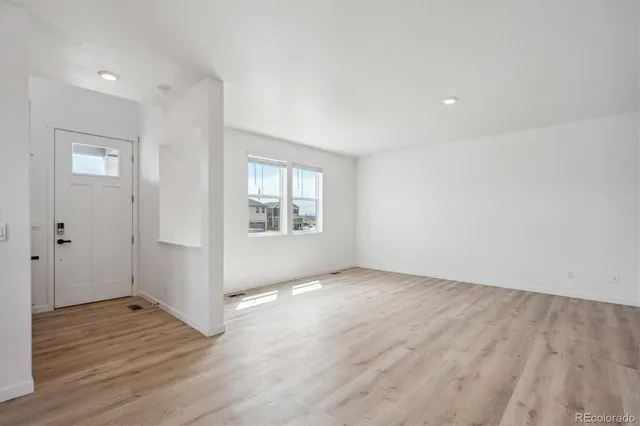 an empty room with wooden floor and windows