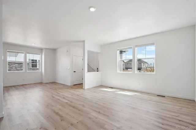an empty room with wooden floor and windows