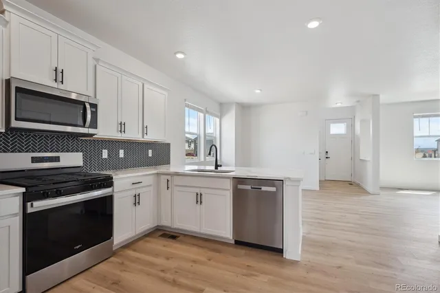 a kitchen with stainless steel appliances granite countertop a stove a sink and a microwave