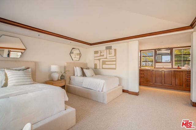a spacious bedroom with a bed a table and painting on the wall