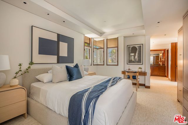 a bedroom with a bed couch and three large window